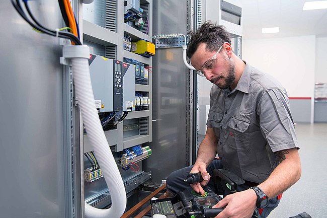 Mitarbeiter bei der Überprüfung eines Schaltschranks in der Elektrotechnik vor der Auslieferung zum Kunden